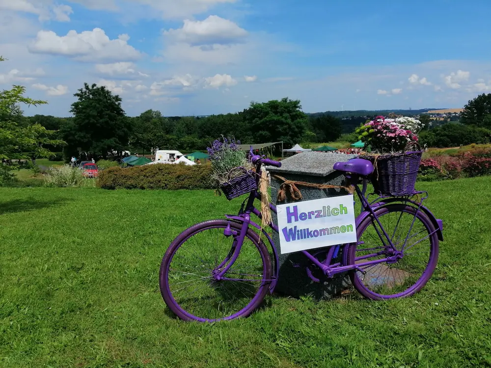 Geschmücktes Fahrrad mit Blumenkorb und Willkommensschild am Eingang